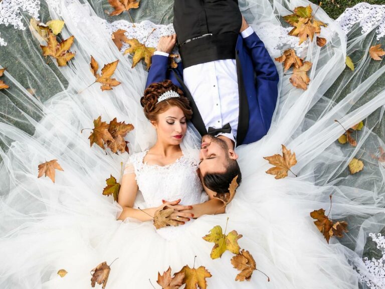 Bride with perfect wedding hair laying in the grass with her husband in a blue suit